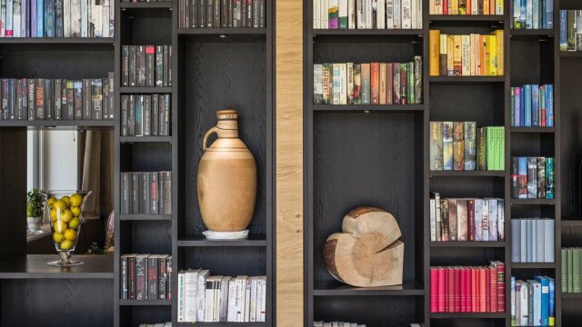 Regal mit Büchern, Vase und Holzskulptur.
