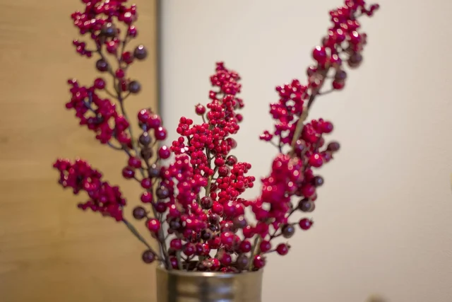 Rote Blütenzweige in einer Metallvase