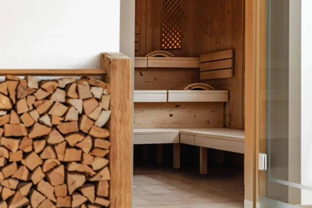 Kleine Sauna mit Holzregal im Hintergrund.