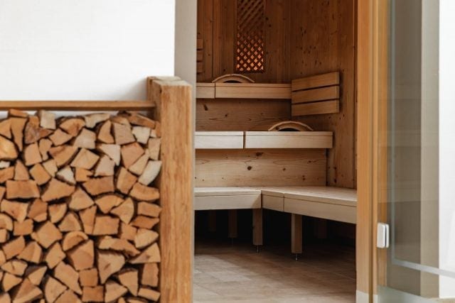 Kleine Sauna mit Holzregal im Hintergrund.