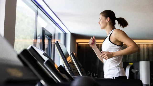 Frau joggt auf einem Laufband im Fitnessstudio.