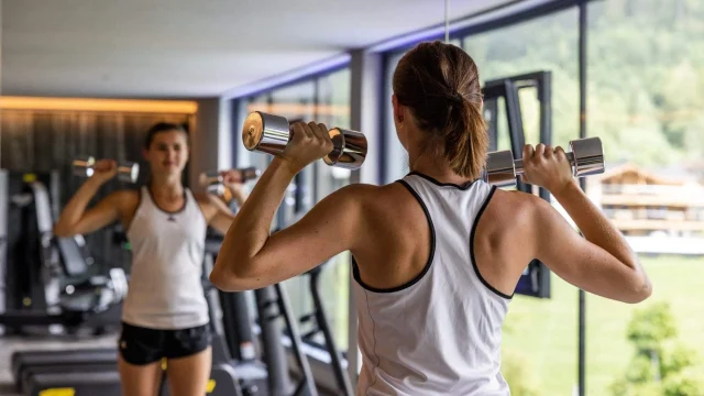 Frau trainiert mit Hanteln im Fitnessstudio.