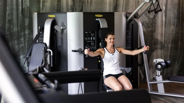 Frau trainiert an Fitnessgerät im Studio.