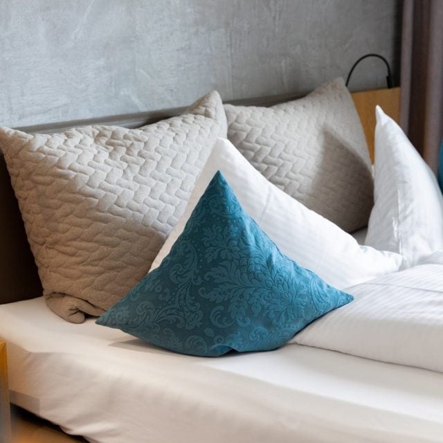 Gemütliches Schlafzimmer mit Kissen und Beleuchtung.