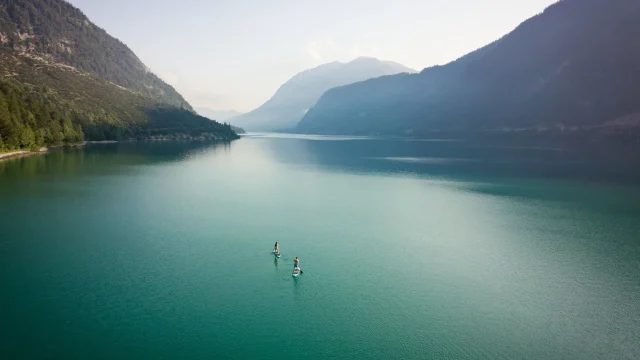 Zwei Personen paddeln auf ruhigem Wasser.