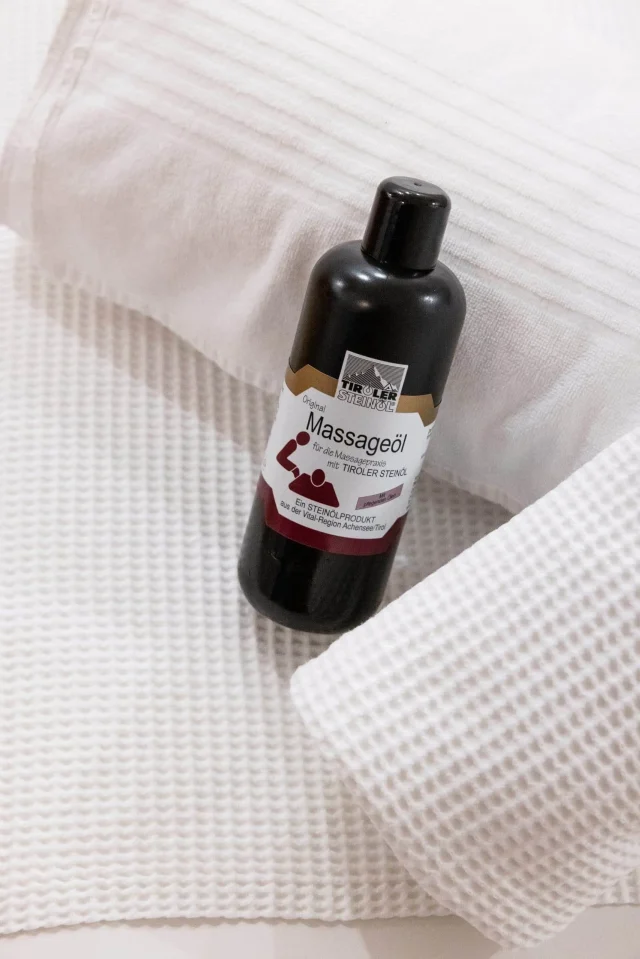 Flasche Massageöl auf weißem Handtuch