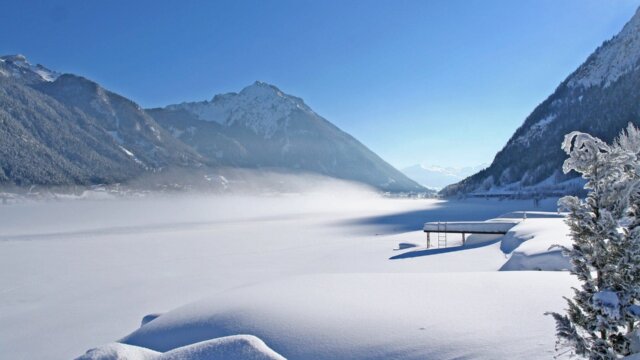 Schneebedeckte Landschaft mit Bergen und See