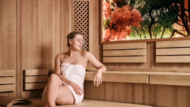 Frau entspannt in einer Sauna mit Holzverkleidung.