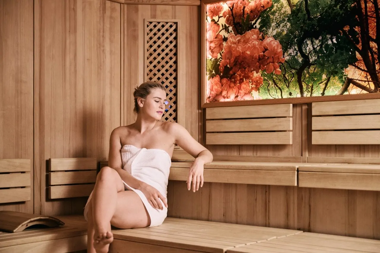 Frau entspannt in einer Sauna mit Holzverkleidung.