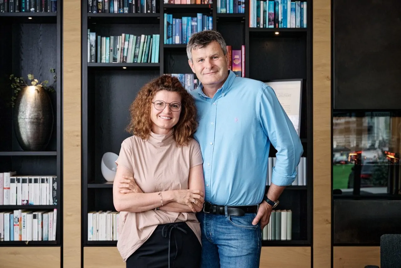 Zwei Personen smiling vor Bücherregal.