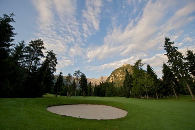 Golfplatz mit Sandbunker und Bergen im Hintergrund