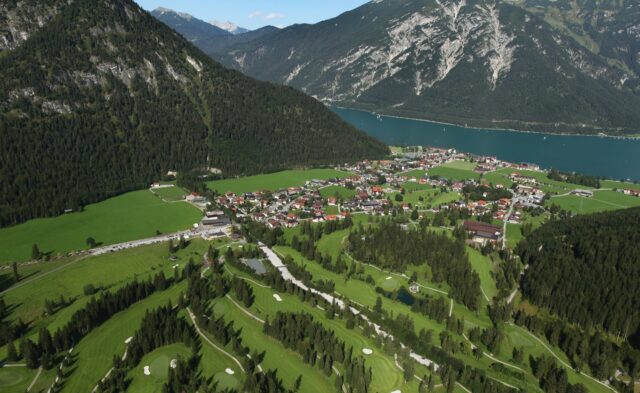 Landschaft mit Bergen, Dorf und Golfplatz.