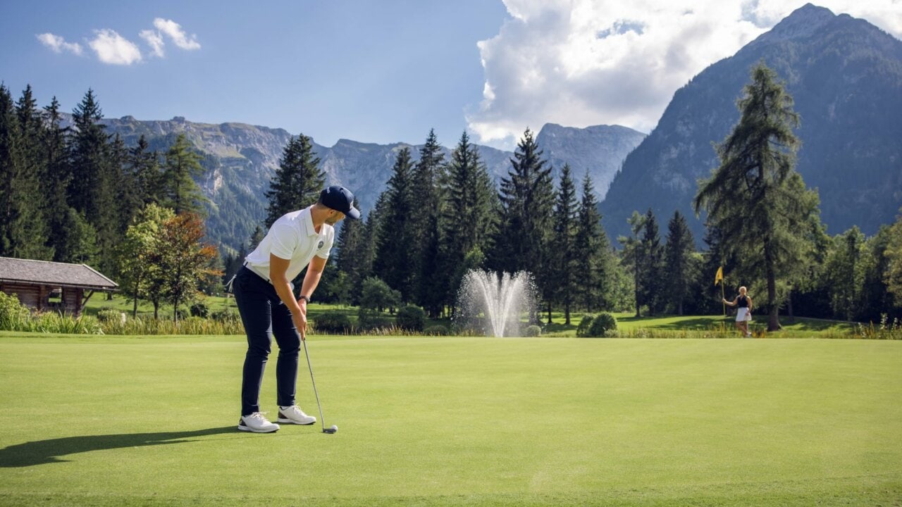 Golfer puttet in malerischer Berglandschaft.
