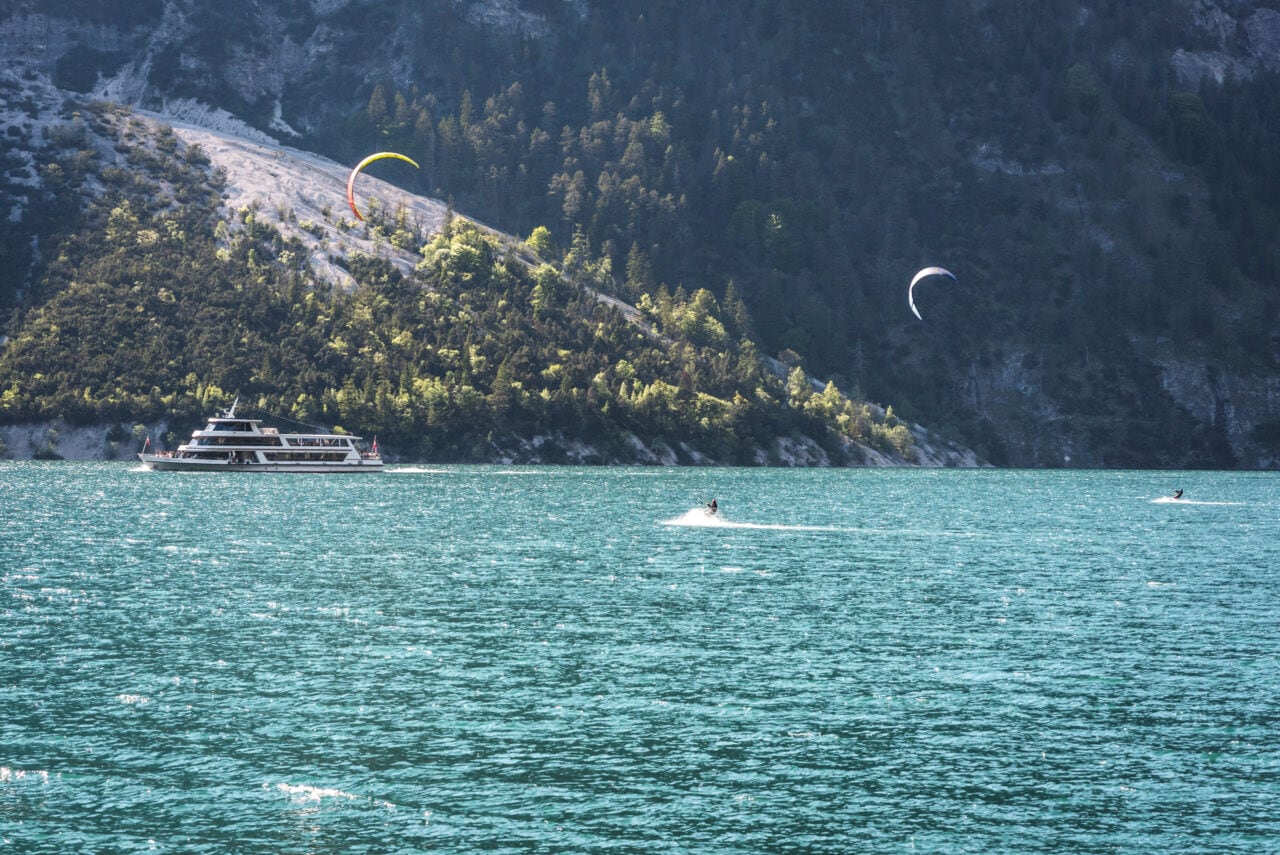 Boot auf einem klaren See mit Kitesurfern.