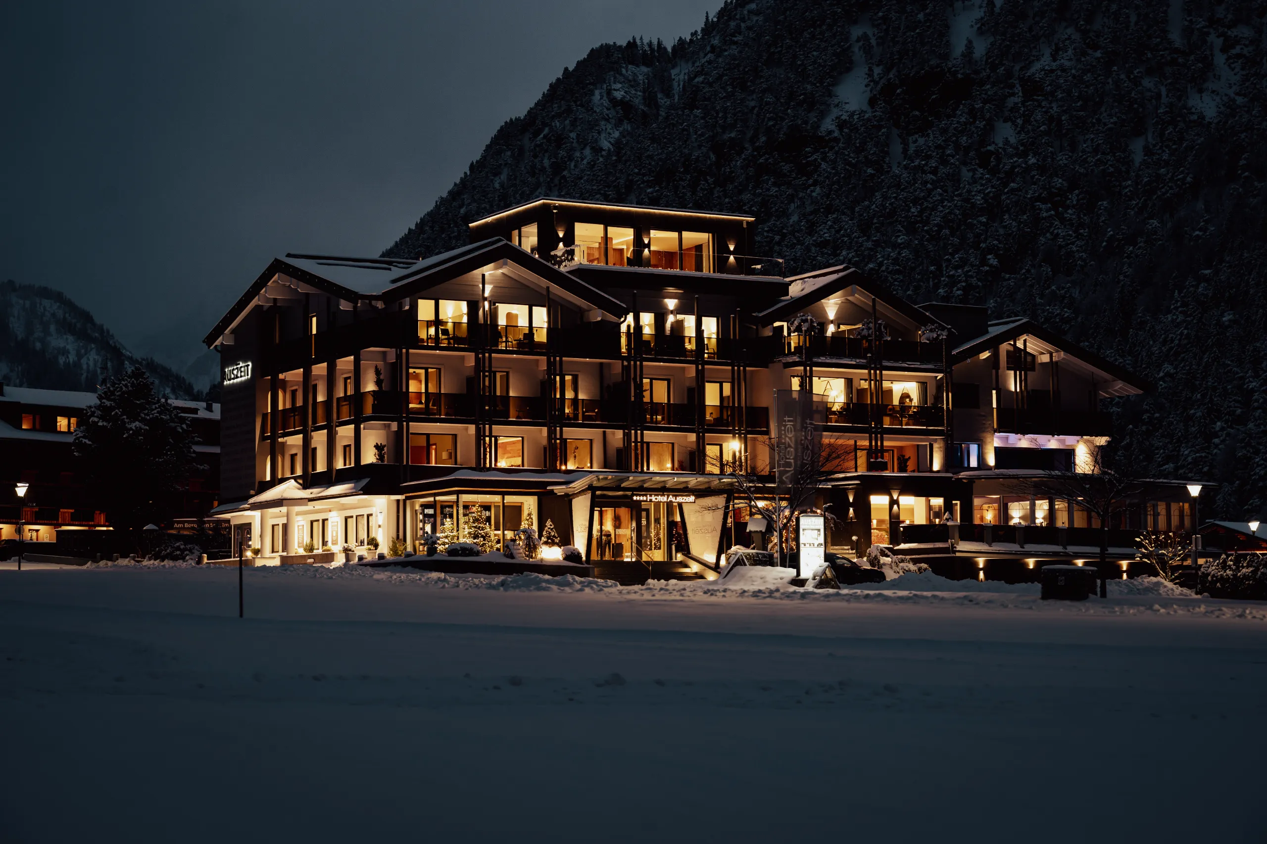 Gemütliches Hotel in verschneiter Berglandschaft bei Nacht.