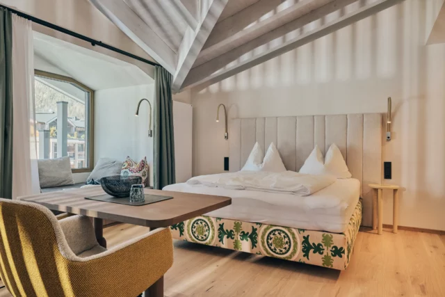 Helles, modernes Zimmer mit Doppelbett und Tisch.