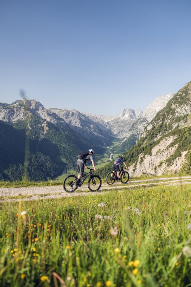 Zwei Radfahrer auf einem Bergweg im Sommer.