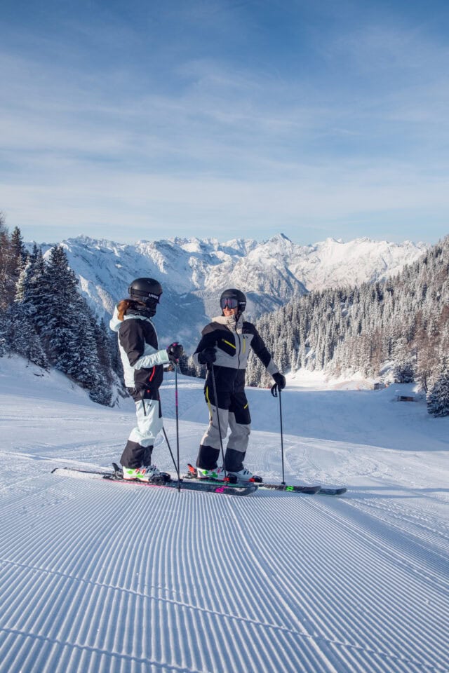 Zwei Skifahrer auf einer verschneiten Piste