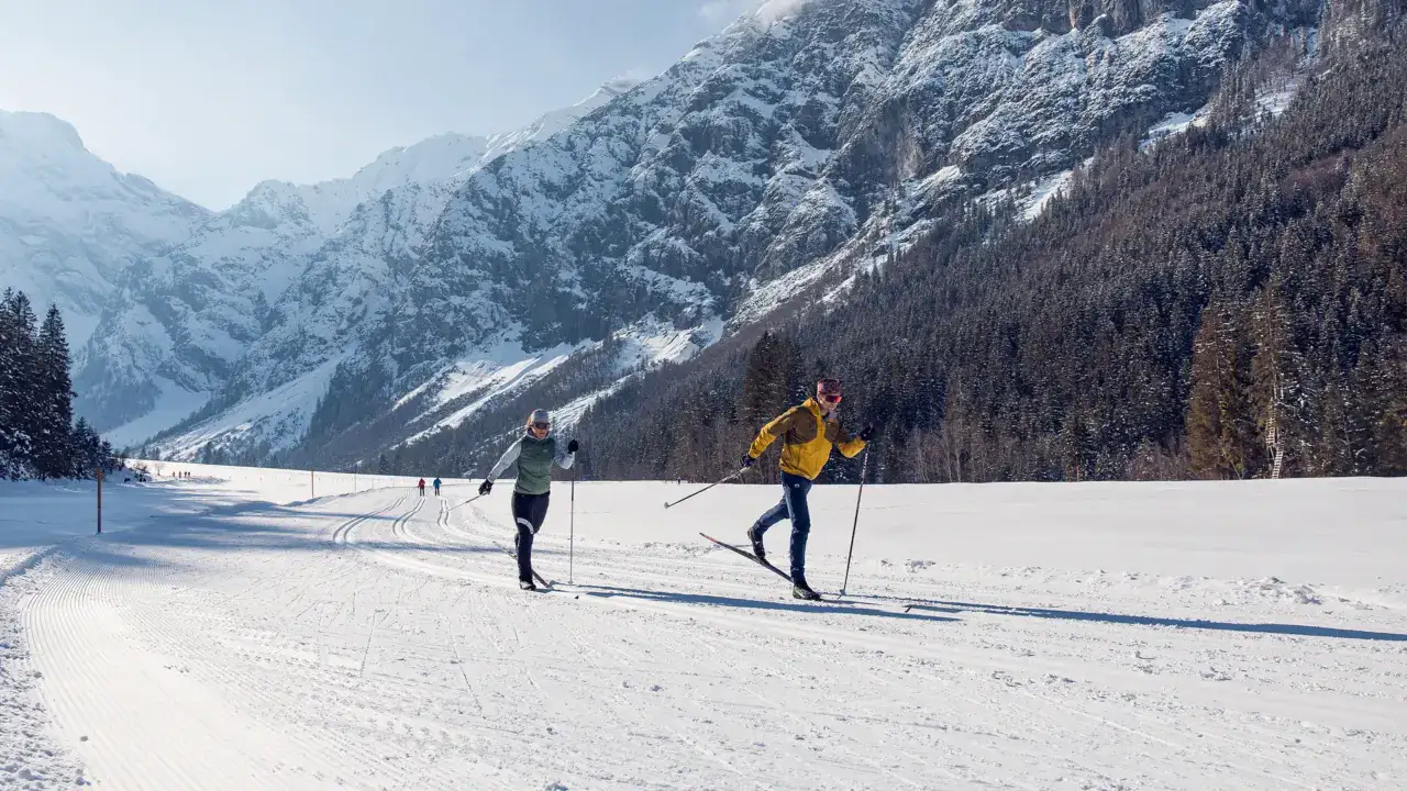 Langläufer auf präparierten Loipen im Achensee, umgeben von verschneiten Bergen. Perfekt für Winters.