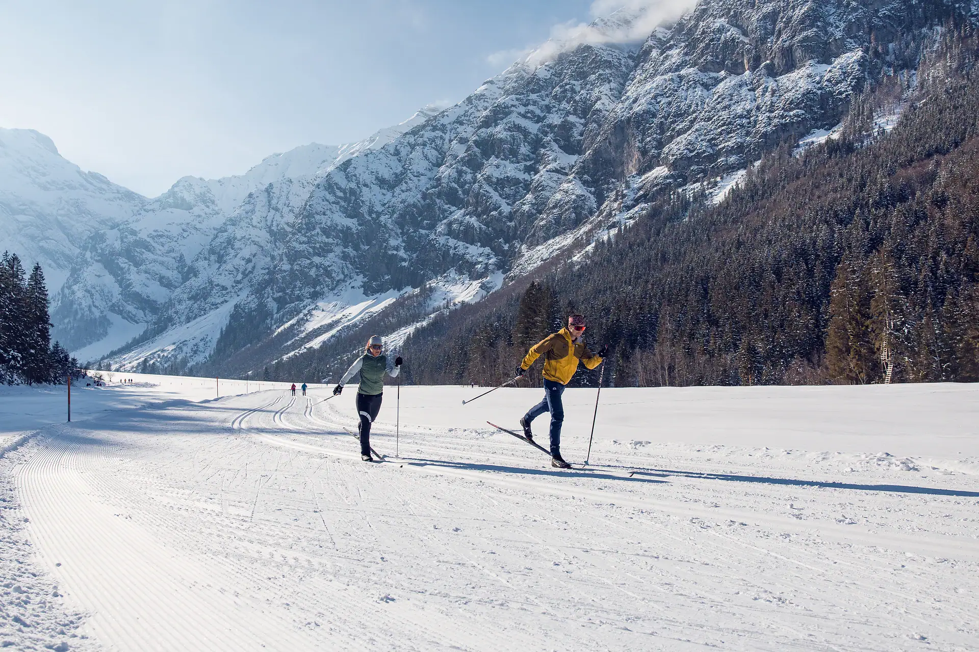 Langläufer auf präparierten Loipen im Achensee, umgeben von verschneiten Bergen. Perfekt für Winters.